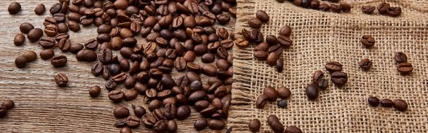 panoramic shot of fresh roasted coffee beans on wooden weather board with sackcloth - Photo, Image
