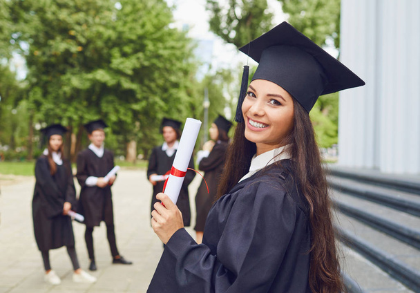A young female graduate against the background of university graduates. - Zdjęcie, obraz