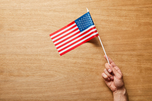 cropped view of man holding american flag on wooden background - Фото, зображення