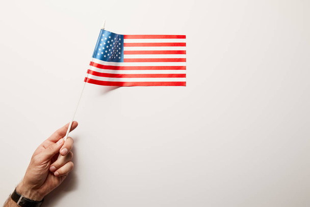 Κορυφαία θέα του ανθρώπου που κρατά αμερικάνικη σημαία σε λευκό φόντο  - Φωτογραφία, εικόνα