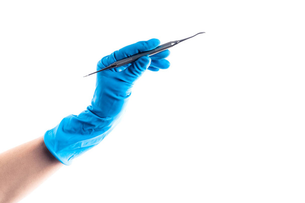 Χέρι με μπλε γάντι κρατώντας το οδοντικό μεταλλικό ραβδί απομονωμένο - Φωτογραφία, εικόνα