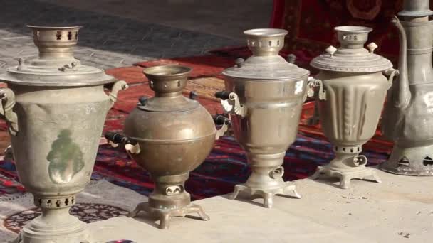 horizontal panorama(side view) of old retro antiques samovars, teapots and jugs, the shopping district of Bukhara, Uzbekistan - Footage, Video