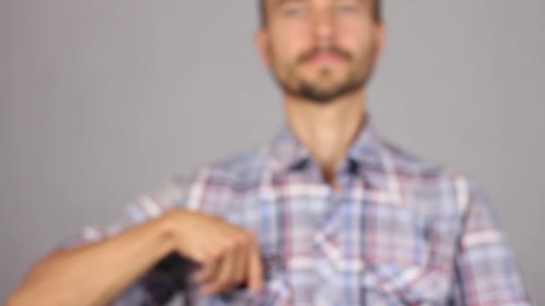 man in geruite hemd trekt uit zijn zak een nieuw condoom, het vertonen van recht uitgestoken hand en glimlach, concept van een gezonde levensstijl en seksuele relaties, grijze achtergrond  - Video