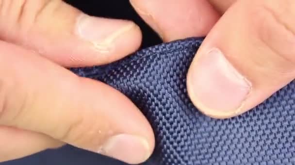 людська рука тестує синій синтетичний матеріал, частина сумки, текстура тканини
 - Кадри, відео