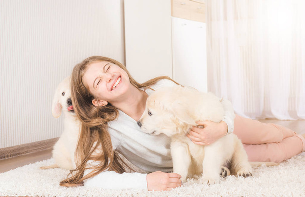 Little girl sit hugging retriever puppies - Valokuva, kuva
