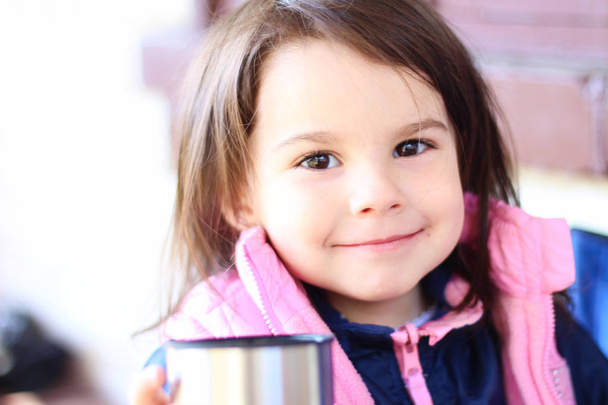 bambina sorridente seduta al tavolo all'aperto
 - Foto, immagini