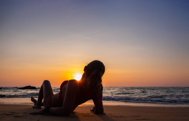 Woman sitting on the beach at sunset  - Fotografie, Obrázek