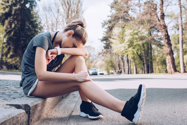 loukkaantunut urheilija itkee istuessaan jalkakäytävällä rajalla ja kärsii kivusta
  - Valokuva, kuva
