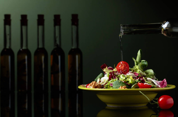 Vihreä salaatti tomaattien, seesamin ja saksanpähkinöiden kanssa, joita kastellaan vihanneksella
 - Valokuva, kuva