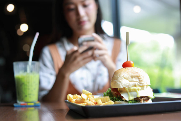 Mujer asiática sonriendo comiendo hamburguesas en el restaurante
  - Foto, imagen