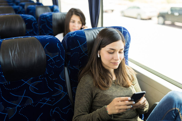 Брюнетка пассажир прослушивания музыки на смартфоне во время путешествия в автобусе
 - Фото, изображение
