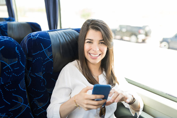 旅行バスで携帯電話を持つ陽気な女性乗客 - 写真・画像