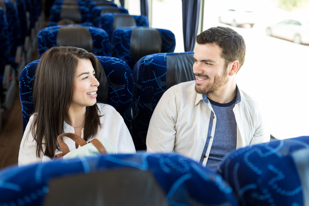 Uśmiechnięte kumple patrząc na siebie podczas podróży w autobusie - Zdjęcie, obraz