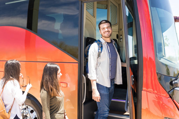 Χαμογελαστός αρσενικός τουρίστας με γυναίκες φίλους επιβίβασης περιοδεία λεωφορείο - Φωτογραφία, εικόνα