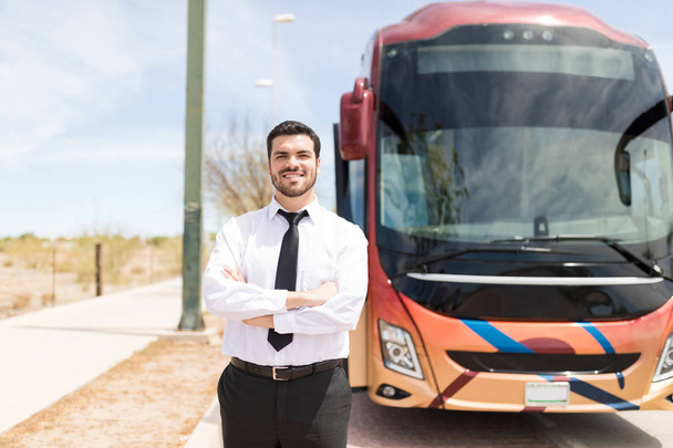 Ammattimainen mieskuljettaja yllään paita ja solmio seisoo lähellä matkustajabussia
 - Valokuva, kuva