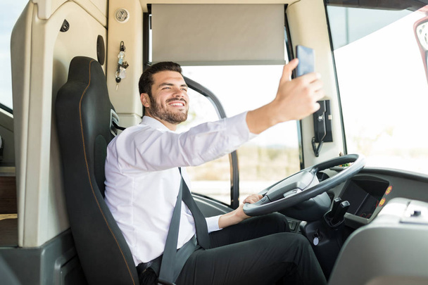 Selbstbewusster junger Fahrer macht Selfie während der Fahrt mit Touristenbus - Foto, Bild