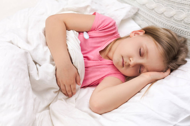 Sick little girl lying in bed with thermometer - Foto, immagini