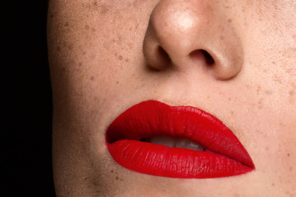 Cosmetics, makeup and trends. Bright lip gloss and red lipstick on lips. Closeup of beautiful female mouth with red lip makeup. Beautiful part of female face. Perfect clean skin in red light - Fotoğraf, Görsel