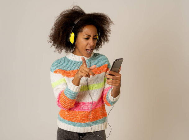 Colorful portrait of gorgeous and happy african american woman listening to smart phone music app in headphones singing and dancing on neutral background. In people Music Technology and Happiness. - Φωτογραφία, εικόνα