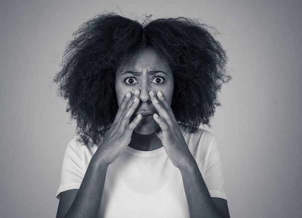 Portret van jonge Afro-Amerikaanse vrouw gevoel bang en geschokt maken angst, angst gebaren. Op zoek doodsbang bedekken zichzelf. Kopieer ruimte. In negatieve menselijke uitdrukkingen en emoties concept. - Foto, afbeelding