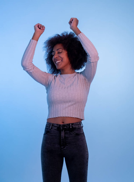 Portrait of inspired cool african american woman dancing feeling the music and enjoying life on blue moody disco light background. In People, Youth Party night lifestyle. Studio shot and copy space. - Fotó, kép