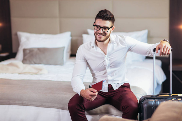 Молодой человек бизнес-путешественник проживание в гостиничном номере
 - Фото, изображение