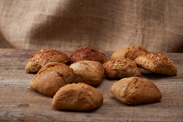 fresh baked buns on wooden table with sackcloth on background - Valokuva, kuva