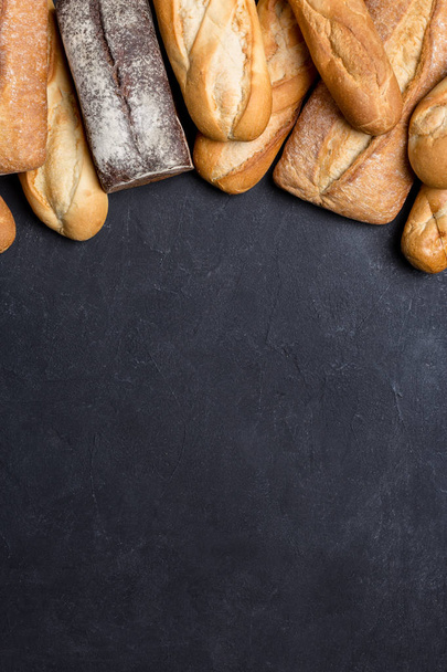 fresh bread on black board, top view with free space - Photo, Image