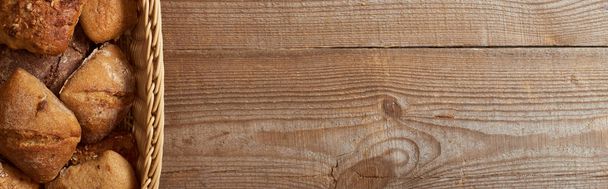 vista superior de la canasta de mimbre con bollos en la mesa de madera, plano panorámico
 - Foto, imagen