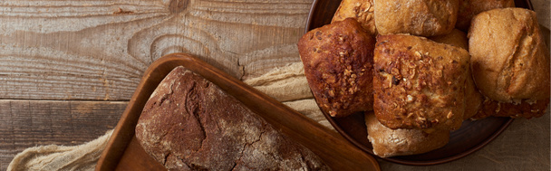 木製のテーブルの上の布のボウルにまな板とパンの新鮮なパンのトップビュー、パノラマショット - 写真・画像