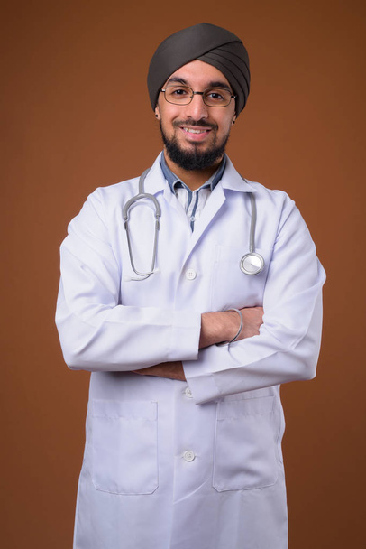 Joven barbudo indio Sikh hombre médico con turbante contra la frente
 - Foto, imagen