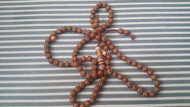 Hermosas cuentas de oración de madera o rosario con un fondo rayado
 - Foto, Imagen