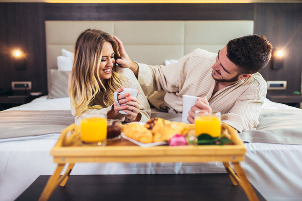 Jovem casal feliz tomando café da manhã no quarto de hotel de luxo
.  - Foto, Imagem