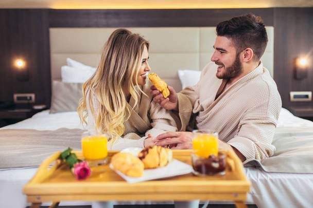 junges glückliches Paar frühstückt im Luxus-Hotelzimmer.  - Foto, Bild
