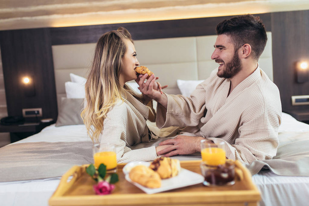Nuori onnellinen pari aamiaisella ylellisessä hotellihuoneessa
.  - Valokuva, kuva