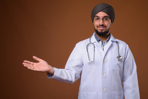 Joven barbudo indio Sikh hombre médico con turbante contra la frente
 - Foto, Imagen