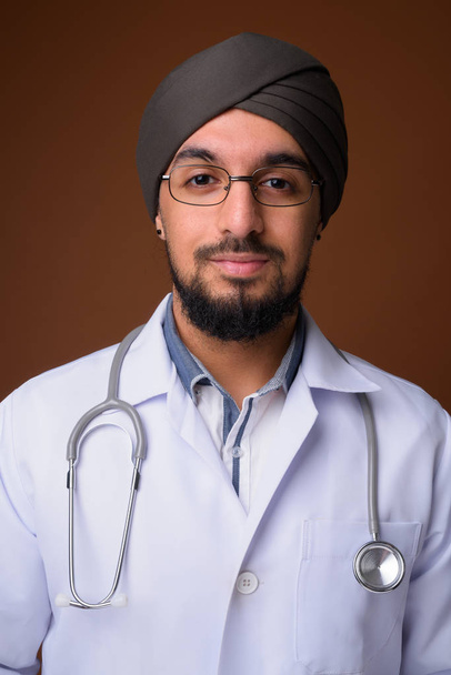 Молодой бородатый индийский сикх врач в тюрбане против бровей
 - Фото, изображение