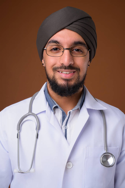 Jeune homme indien barbu médecin sikh portant turban contre le front
 - Photo, image