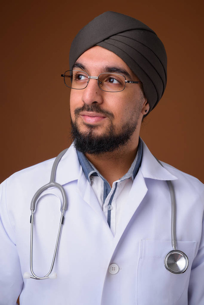 Joven barbudo indio Sikh hombre médico con turbante contra la frente
 - Foto, Imagen