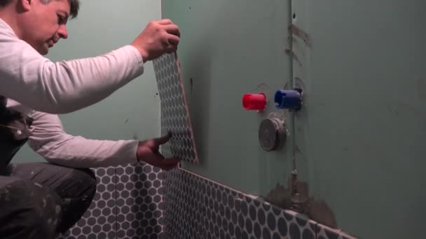 熟練した労働者は、バスルームの壁にレイタイルをインストールします - 映像、動画