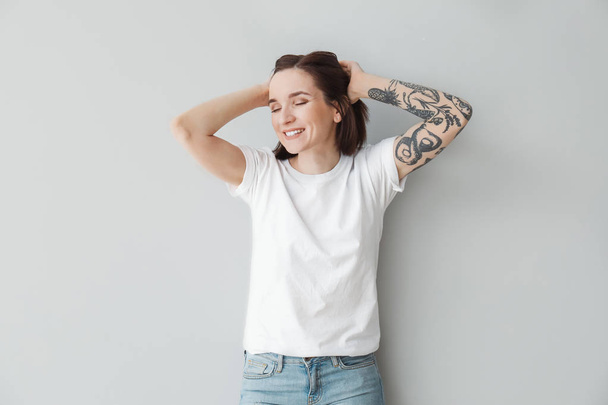 Stylish tattooed woman on light background - Photo, Image