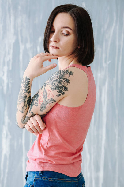 Hermosa mujer tatuada cerca de la pared grunge
 - Foto, imagen