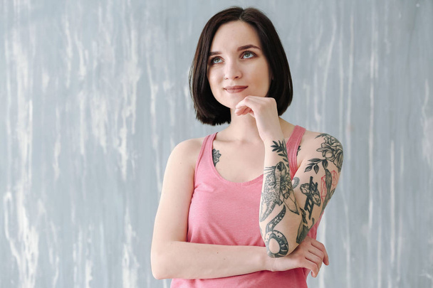Gyönyörű tetovált nő közelében grunge fal - Fotó, kép
