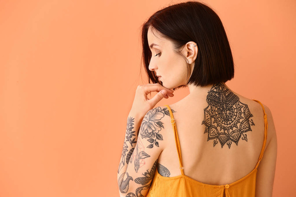 Beautiful tattooed woman on color background - Фото, зображення