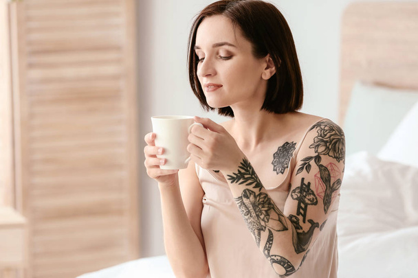Hermosa mujer tatuada bebiendo café por la mañana en casa
 - Foto, Imagen