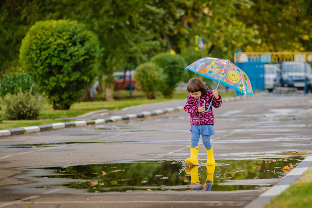 多色の傘がゴムブーツで水たまりをジャンプし、笑う幸せな面白い子供 - 写真・画像