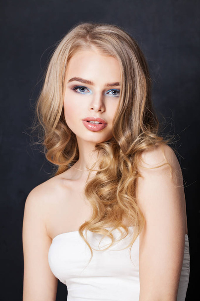 Mooie vrouw met lange blonde haren en make-up op zwart  - Foto, afbeelding