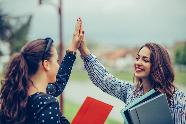 Dos estudiantes mujeres felices están dando cinco altos después del éxito
 - Foto, imagen