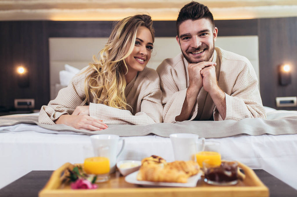 Joven pareja feliz desayunando en habitación de hotel de lujo
.  - Foto, imagen