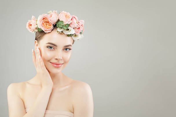 Jonge glimlachende vrouw met gezonde huid en roze rozen bloemen  - Foto, afbeelding